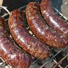 Cztery kaszanki na grillu. Zastanawiasz się, czy kaszankę można mrozić? Tak, można ją zamrozić, by cieszyć się smakiem później.