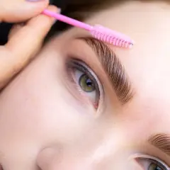 Stylist czesze brwi szczoteczką po zabiegu laminacji. Zabieg można powtarzać co 4-6 tygodni.