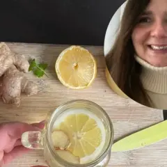 Kobieta przygotowuje orzeźwiającą wodę z cytryną i imbirem. Na desce leżą świeże korzenie imbiru i plaster cytryny.