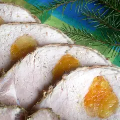 Pokrojony schab z morelami, pachnący świętami, ozdobiony gałązką iglastą na kolorowym tle.