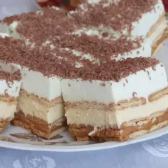 Pyszne ciasto z herbatnikami, kremem i karmelem, posypane wiórkami czekoladowymi. Idealne na deser!