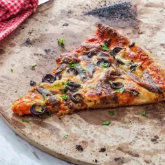 Kawałek pizzy z anchois i oliwkami na kamieniu. Dowiedz się, jak wyczyścić kamień do pizzy, by był jak nowy.
