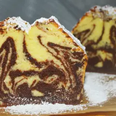 Wilgotna babka marmurkowa na oleju, oprószona cukrem pudrem. Jej puszyste ciasto z kontrastowymi pasmami czekolady zachęca do spróbowania.