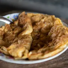 Puszysty omlet na słodko, lekko zarumieniony, podany na talerzyku z kwiatowym wzorem. Idealny na słodkie śniadanie.