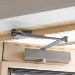 Mechanizm samozamykacza drzwi, zamontowany na futrynie, zapewnia płynną regulację domykania.