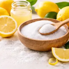 Składniki do domowych kosmetyków: cytryny, sok z cytryny i biały proszek, który jest kluczowy jako citric acid w kosmetykach.