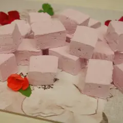 Różowe pianki marshmallow, idealne do domowego przepisu. Ułożone na wzorzystym tle, ozdobione kwiatami.