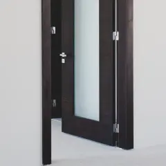 Ciemna, drewniana futryna z ościeżnicą i matowym przeszkleniem, otwierająca przejście do innego pomieszczenia.