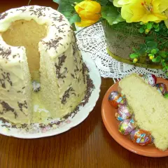 Babka gotowana przepis: puszyste ciasto z lukrem i posypką, obok kawałek z czekoladowymi jajeczkami.