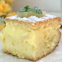 Puszyste ciasto z ananasem z puszki i budyniem, posypane cukrem pudrem i udekorowane miętą.