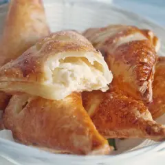 Chrupiące ciasto francuskie z kremowym twarogiem, posypane cukrem, w białym koszyku. Idealne na deser.