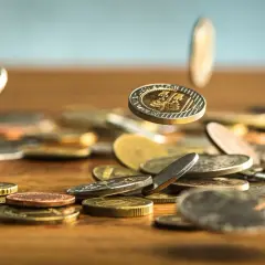 Monety spadają na drewniany blat. Zastanawiasz się, jak wyczyścić monety domowym sposobem? Oto kilka wskazówek.