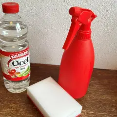 Butelka octu, czerwony spryskiwacz i gąbka do czyszczenia granitu octem.
