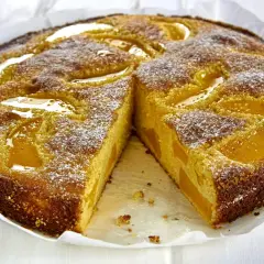 Pyszne ciasto z serem i brzoskwiniami, posypane cukrem pudrem. Idealne na deser.