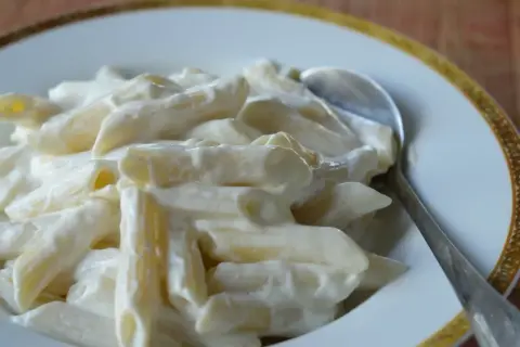 Penne w kremowym sosie serowym, idealne na słodko. Łyżka czeka, by zanurzyć się w tej pyszności.