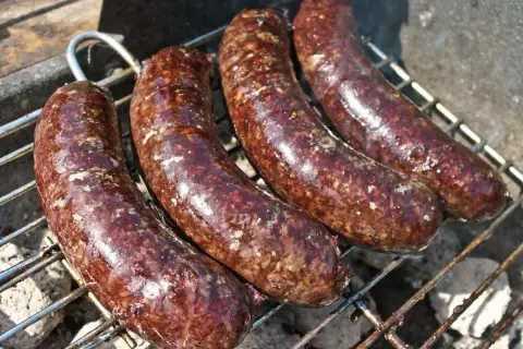 Cztery kaszanki na grillu. Zastanawiasz się, czy kaszankę można mrozić? Tak, można ją zamrozić, by cieszyć się smakiem później.