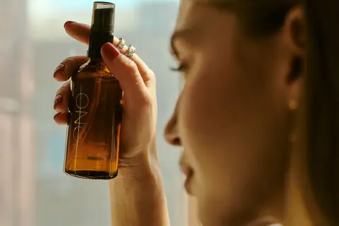 Kobieta trzyma buteleczkę z mgiełką. Czy cetearyl alcohol to składnik tej mgiełki?