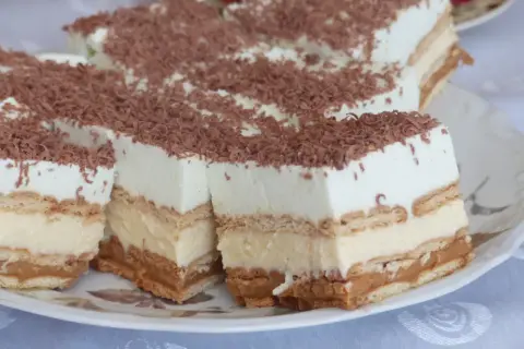 Pyszne ciasto z herbatnikami, kremem i karmelem, posypane wiórkami czekoladowymi. Idealne na deser!