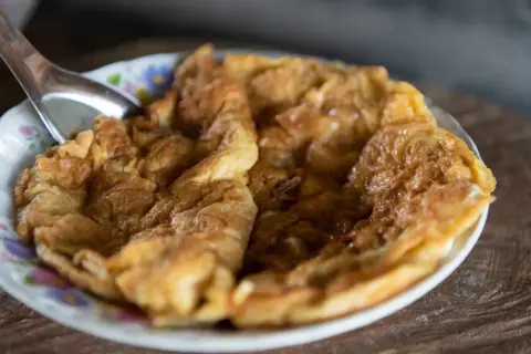 Puszysty omlet na słodko, lekko zarumieniony, podany na talerzyku z kwiatowym wzorem. Idealny na słodkie śniadanie.