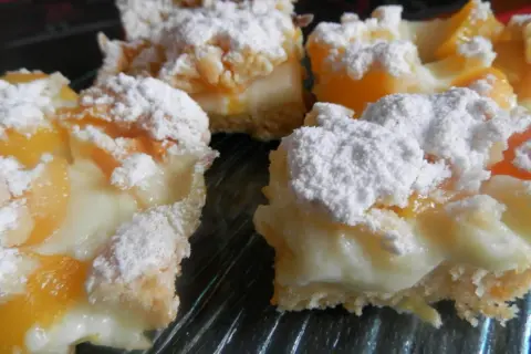 Pyszne ciasto z brzoskwiniami z puszki i budyniem, posypane cukrem pudrem. Idealne na deser!