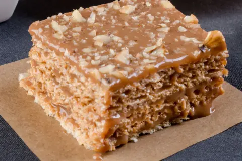 Warstwowe wafle z kremem kajmakowym, posypane orzechami. Pyszny deser, który rozpływa się w ustach.