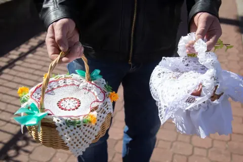 Dwie ozdobne koszyczki do święconki, jeden z koronką i kwiatkami, drugi przykryty białą tkaniną.