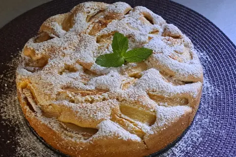 Szybki jabłecznik na oleju, posypany cukrem pudrem i udekorowany listkiem mięty. Idealny na deser.