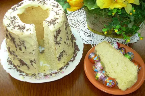 Babka gotowana przepis: puszyste ciasto z lukrem i posypką, obok kawałek z czekoladowymi jajeczkami.
