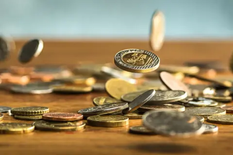 Monety spadają na drewniany blat. Zastanawiasz się, jak wyczyścić monety domowym sposobem? Oto kilka wskazówek.