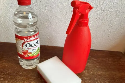 Butelka octu, czerwony spryskiwacz i gąbka do czyszczenia granitu octem.