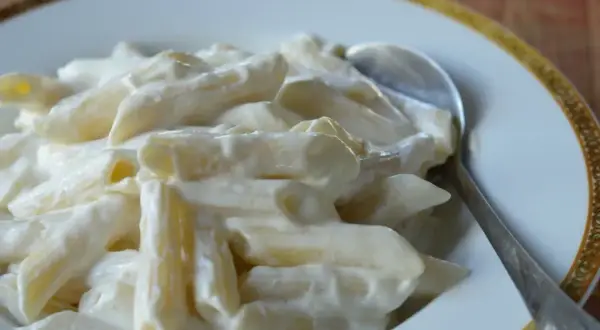 Penne w kremowym sosie serowym, idealne na słodko. Łyżka czeka, by zanurzyć się w tej pyszności.
