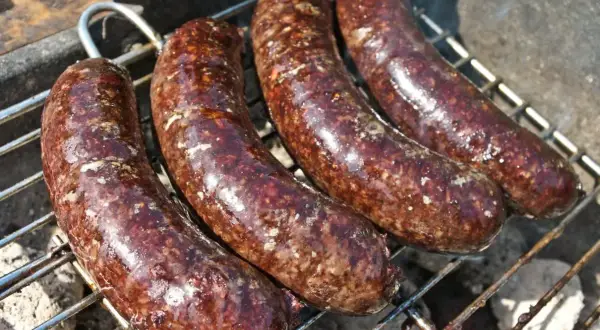 Cztery kaszanki na grillu. Zastanawiasz się, czy kaszankę można mrozić? Tak, można ją zamrozić, by cieszyć się smakiem później.