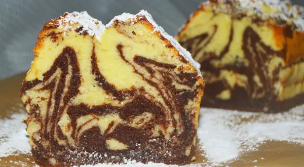 Wilgotna babka marmurkowa na oleju, oprószona cukrem pudrem. Jej puszyste ciasto z kontrastowymi pasmami czekolady zachęca do spróbowania.