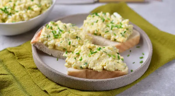 Pyszna pasta jajeczna ze szczypiorkiem na kromkach chleba. Idealna na śniadanie lub przekąskę.