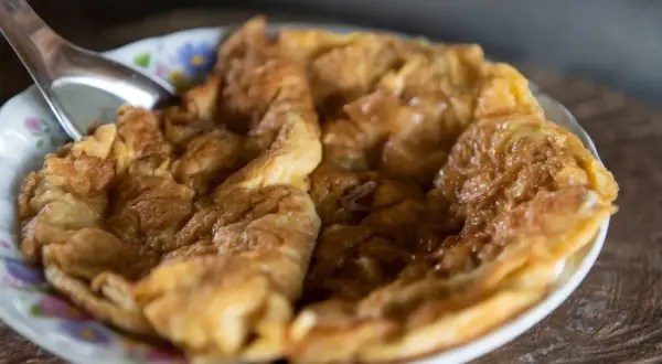 Puszysty omlet na słodko, lekko zarumieniony, podany na talerzyku z kwiatowym wzorem. Idealny na słodkie śniadanie.