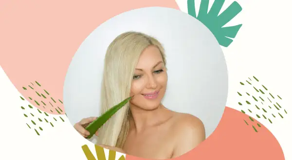 Blondynka z uśmiechem dotyka swoich włosów liściem aloesu, który jest naturalnym kosmetykiem do pielęgnacji włosów.