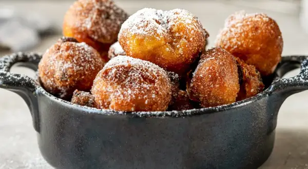 Puszyste paczki z serka homo, posypane cukrem pudrem, kuszą swoim złotym kolorem i apetycznym wyglądem.