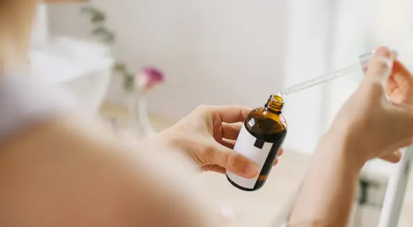 Kobieta aplikuje serum z pipetką na dłoń. Bezpieczny niacynamid w ciąży to klucz do zdrowej skóry.