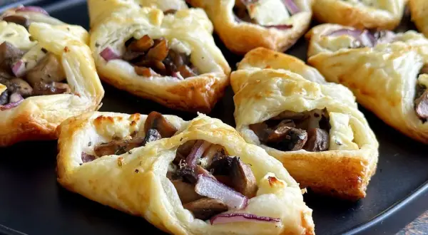 Pyszne przekąski z ciasta francuskiego z pieczarkami, serem i czerwoną cebulą.