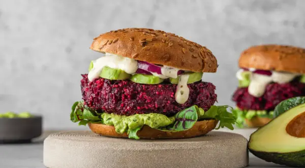 Pyszny burger z buraka z awokado, czerwoną cebulą i kremowym sosem. Idealna wegetariańska alternatywa.