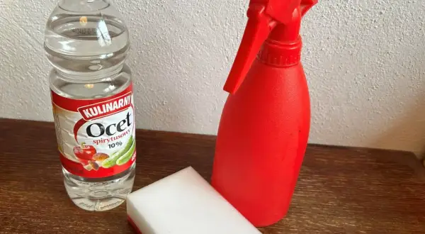 Butelka octu, czerwony spryskiwacz i gąbka do czyszczenia granitu octem.
