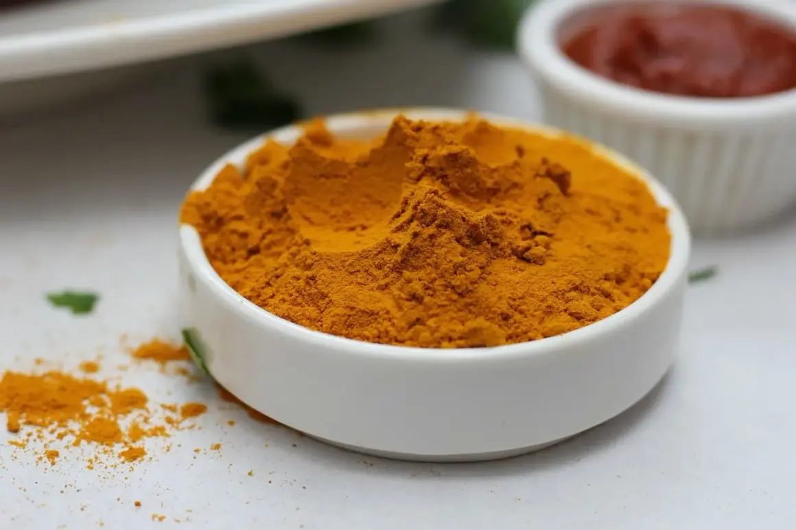 Jasnożółta kurkuma w proszku w białej miseczce, idealna do curry, zup i napojów. Kurkuma do czego? Do zdrowia i smaku!