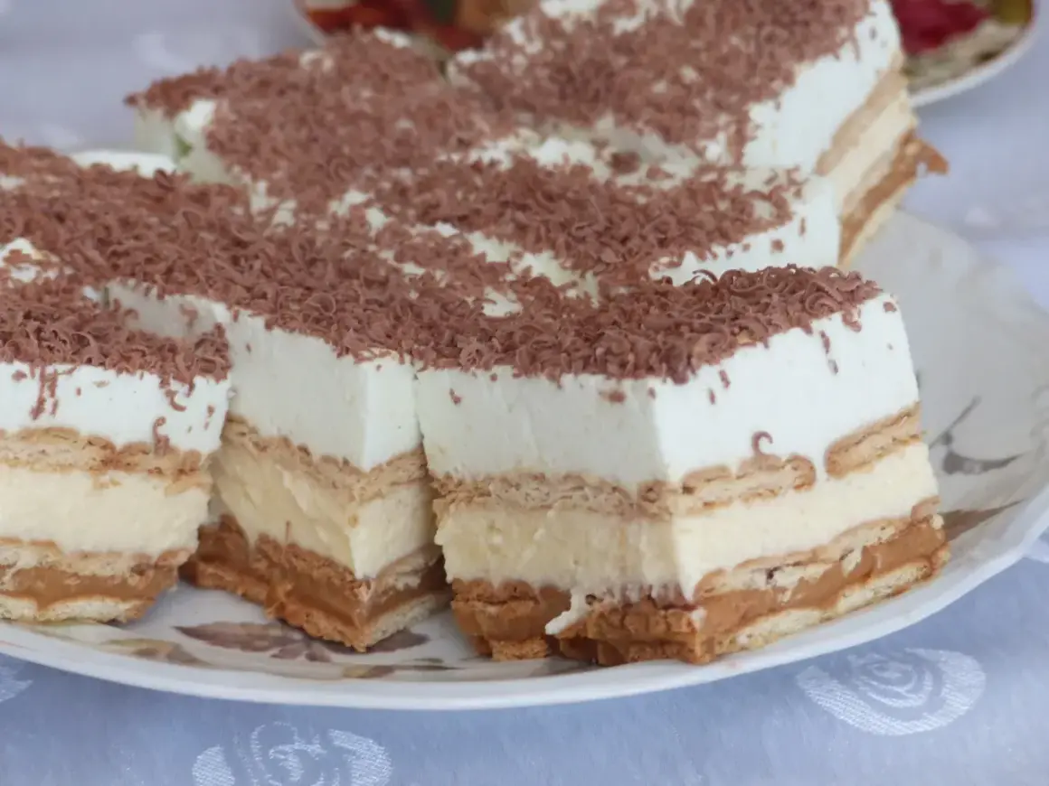 Pyszne ciasto z herbatnikami, kremem i karmelem, posypane wiórkami czekoladowymi. Idealne na deser!