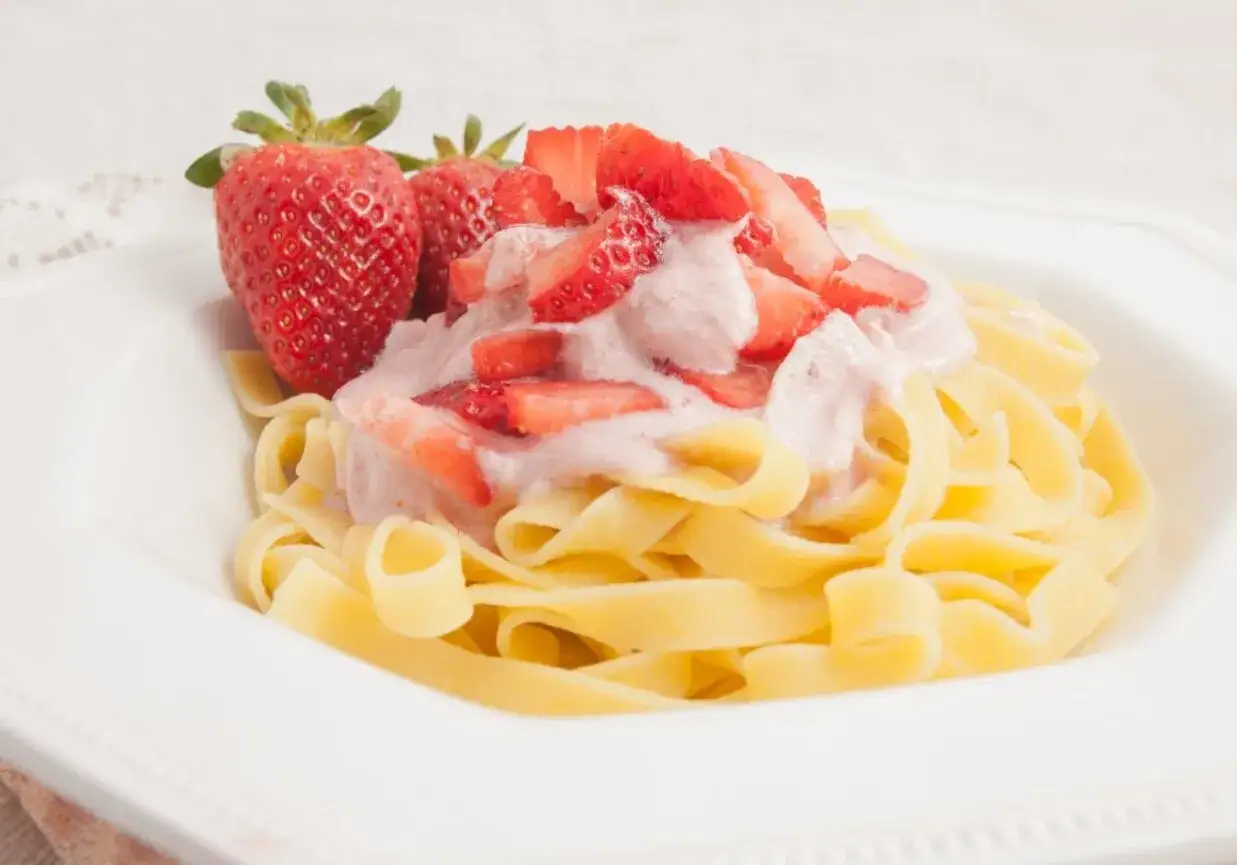 Tagliatelle z kremowym sosem truskawkowym i świeżymi truskawkami. Pyszny deser lub nietypowe danie obiadowe.
