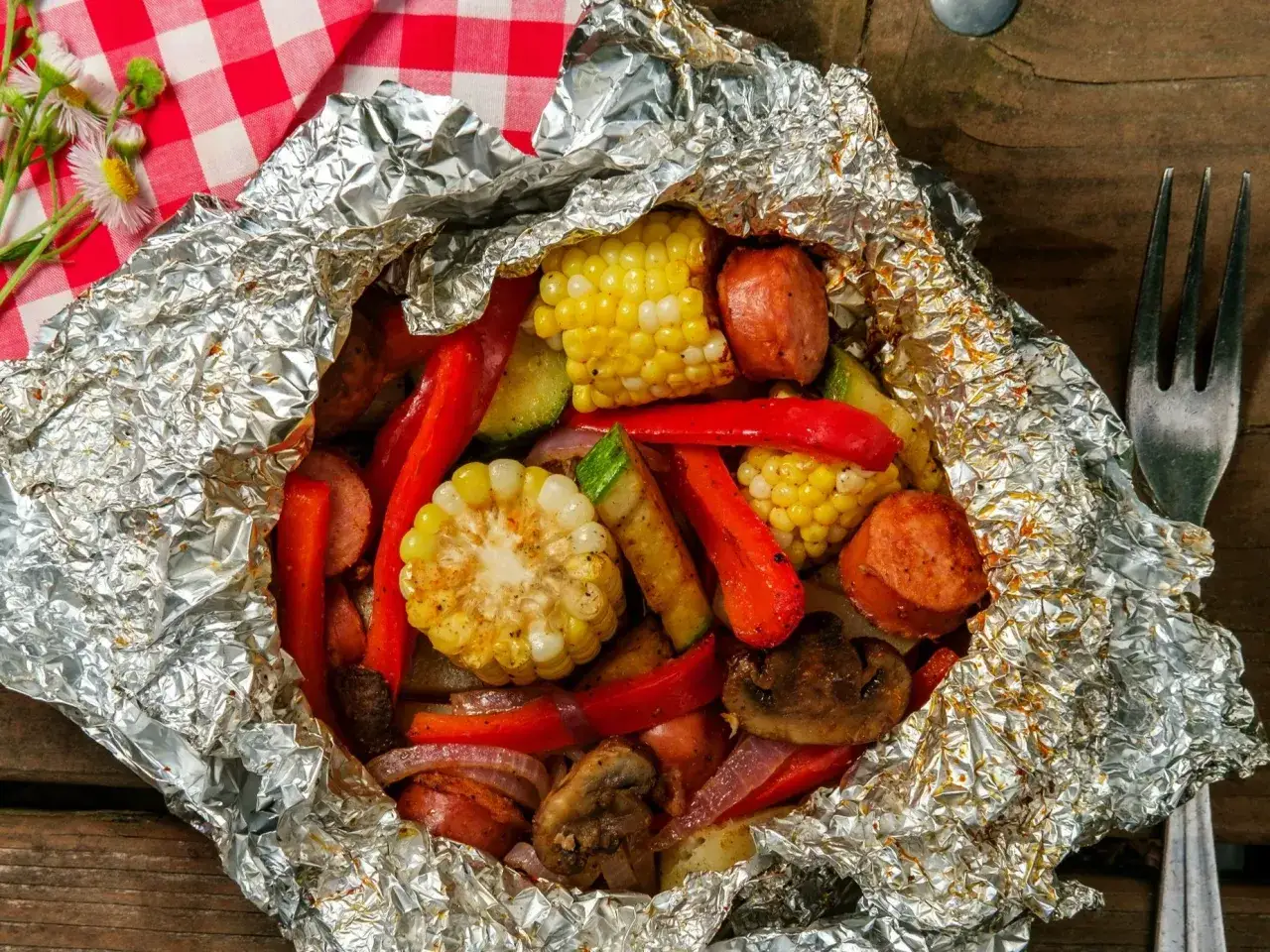 Foliowe paczuszki z kukurydzą, papryką, kiełbasą i pieczarkami – idealne tanie pomysły na grilla.