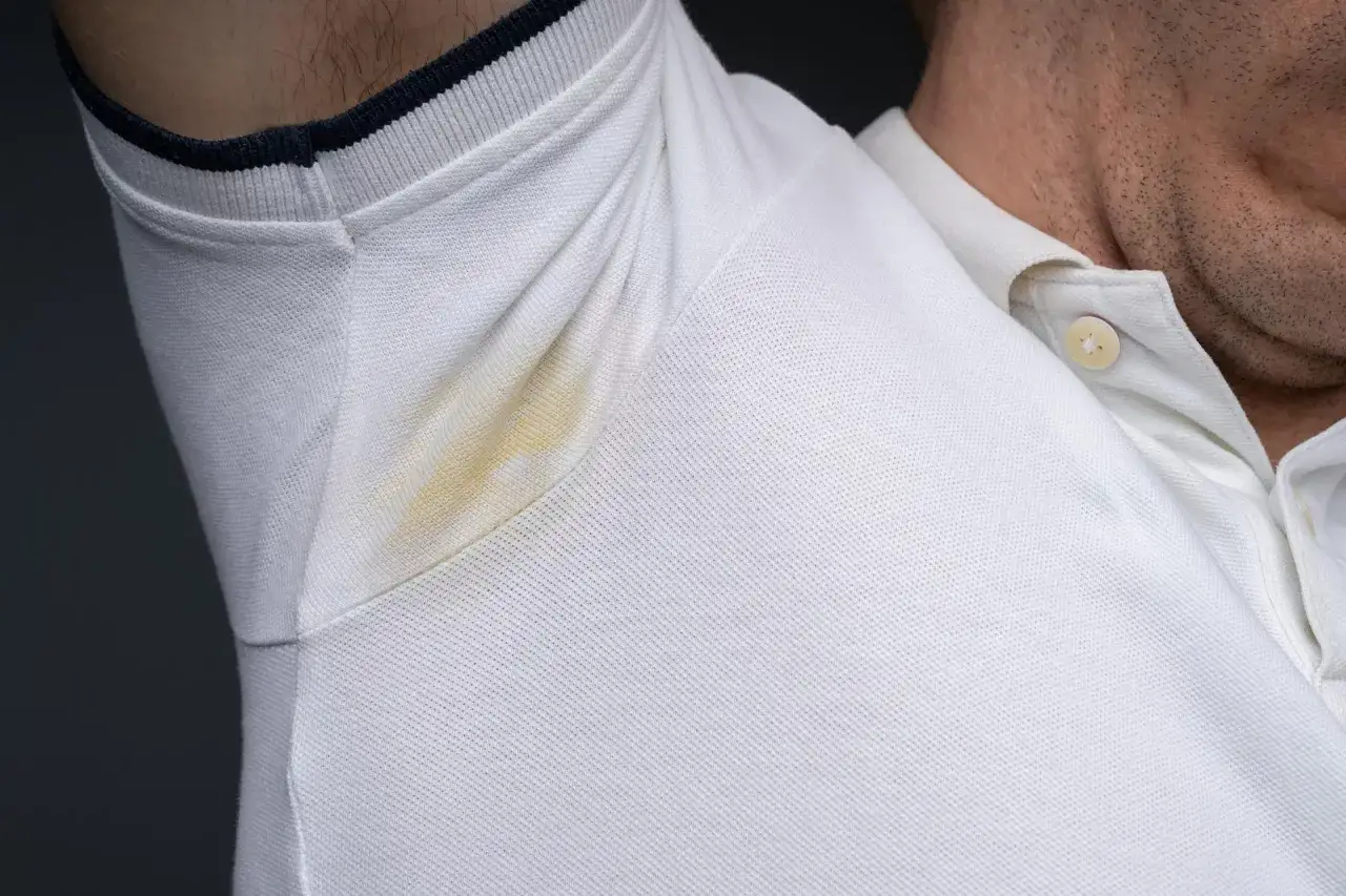 Widoczne żółte plamy pod pachami na białej koszulce polo. Problem, który dotyka wielu z nas, zwłaszcza w upalne dni.