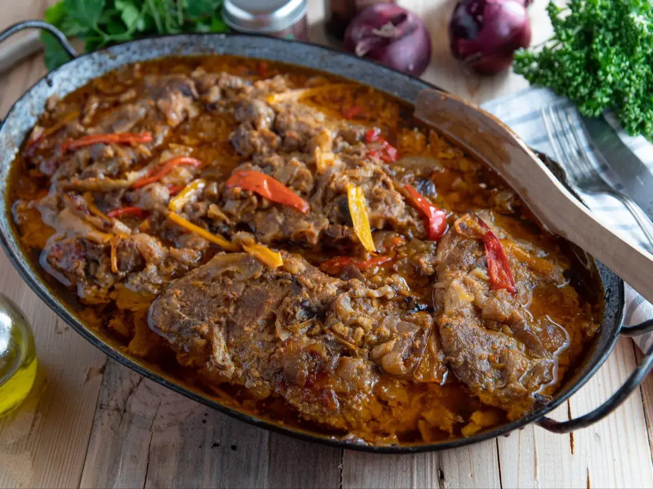Pyszne potrawy z karkówki w sosie z papryką i cebulą, idealne na przyjęcie. Aromatyczne danie w metalowej patelni.