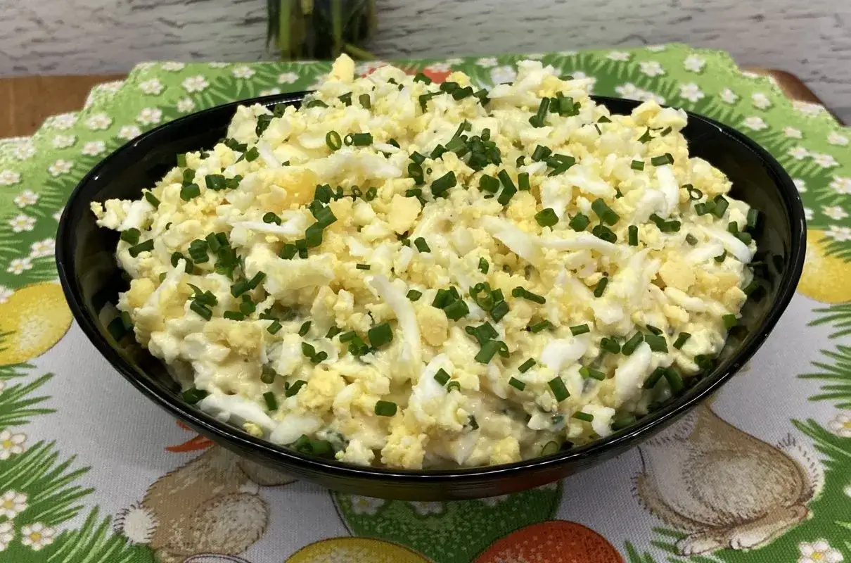 Pyszna pasta jajeczna z chrzanem, posypana szczypiorkiem, w czarnej misce na wielkanocnym obrusie.