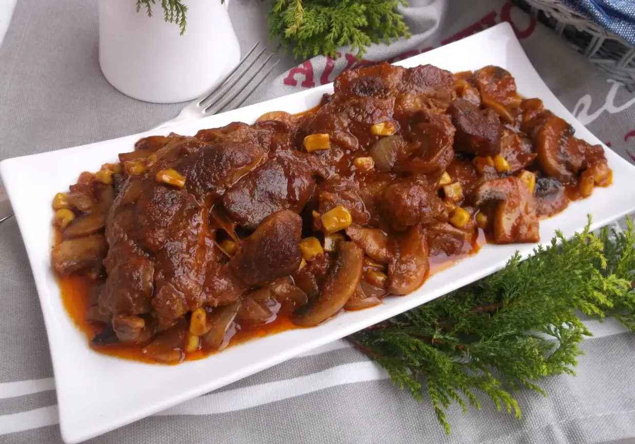 Pyszne potrawy z karkówki na przyjęcie, duszone z pieczarkami i kukurydzą w aromatycznym sosie.