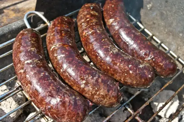 Cztery kaszanki na grillu. Zastanawiasz się, czy kaszankę można mrozić? Tak, można ją zamrozić, by cieszyć się smakiem później.